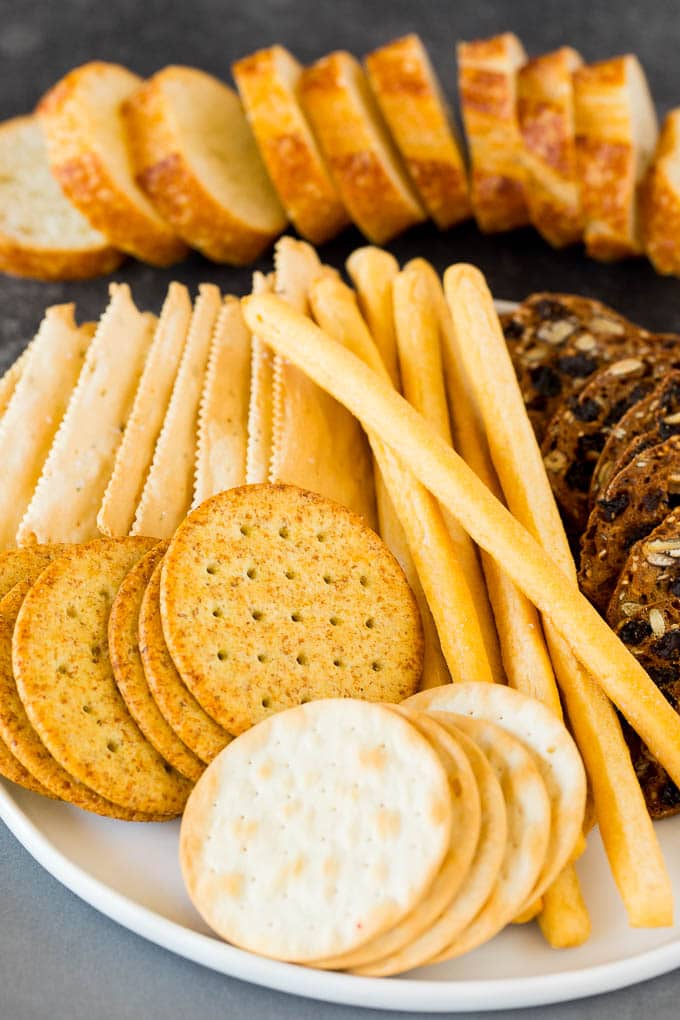 A guide to creating the best cheese board with a variety of different cheeses, crackers, fruit and accompaniments. A plate of crackers and breadsticks.