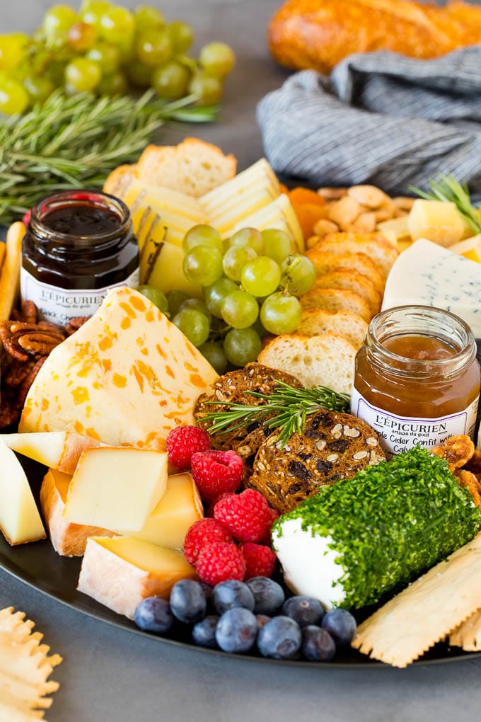 A guide to creating the best cheese board with a variety of different cheeses, crackers, fruit and accompaniments. A cheese board with crackers, fruit, nuts and jam.