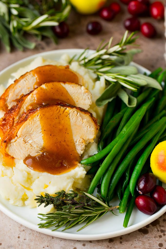 This Instant Pot turkey breast is seasoned with butter, garlic and herbs, then pressure cooked to tender and juicy perfection. Instant Pot turkey breast sliced and served with mashed potatoes and gravy.