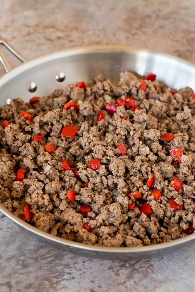 This picadillo is a blend of ground beef, olives and vegetables, all simmered together with spices and tomato sauce. Ground beef and bell peppers in a skillet.