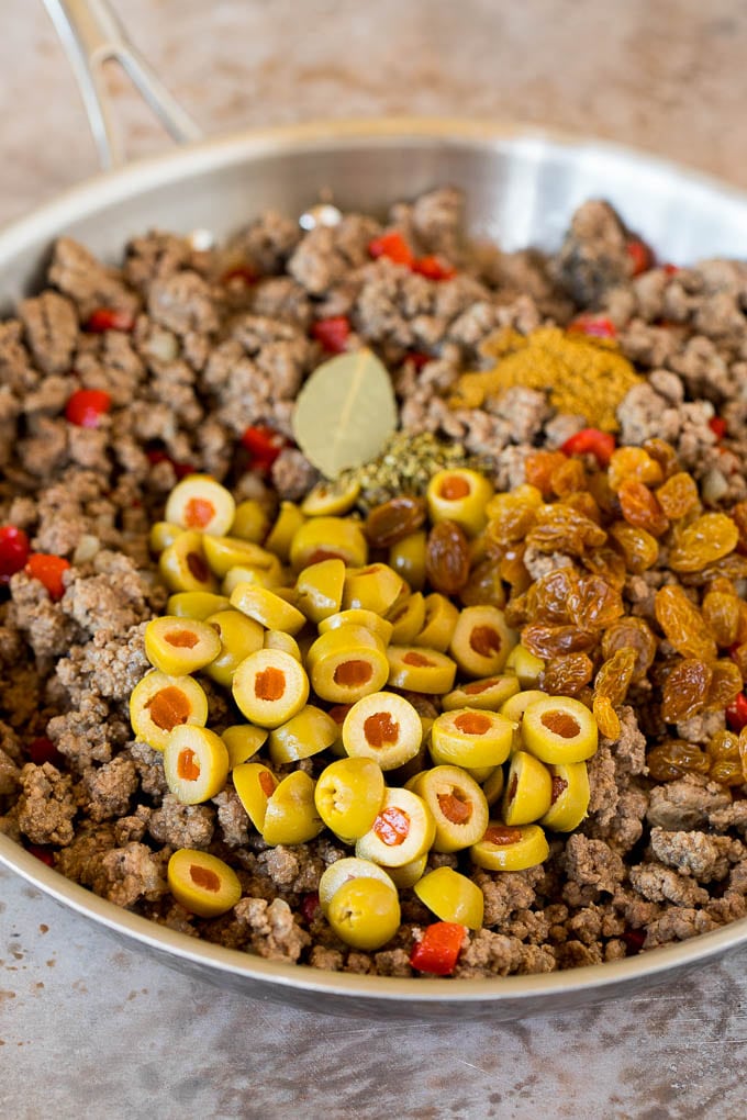 This picadillo is a blend of ground beef, olives and vegetables, all simmered together with spices and tomato sauce. Cooked ground beef with olives, raisins and spices.