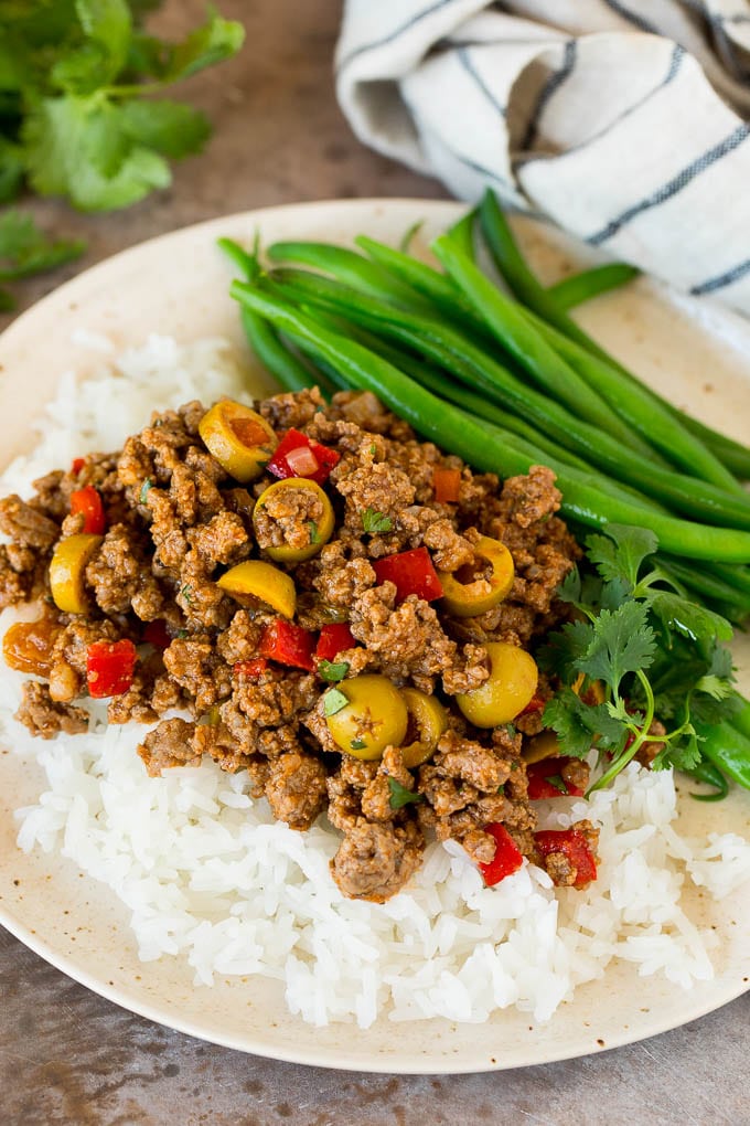 This picadillo is a blend of ground beef, olives and vegetables, all simmered together with spices and tomato sauce. Picadillo served over rice with a side of green beans.