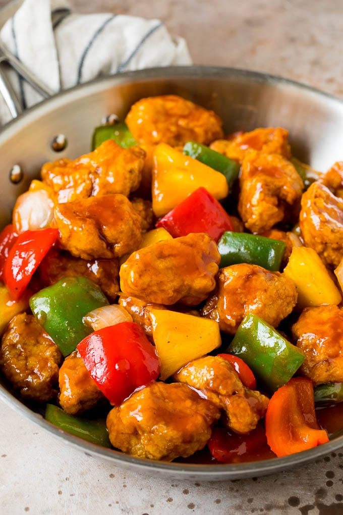 This sweet and sour pork is chunks of pork tenderloin that are breaded and fried, then tossed with pineapple and fresh vegetables in a homemade sauce. Sweet and sour pork with pineapple and bell peppers in a skillet.