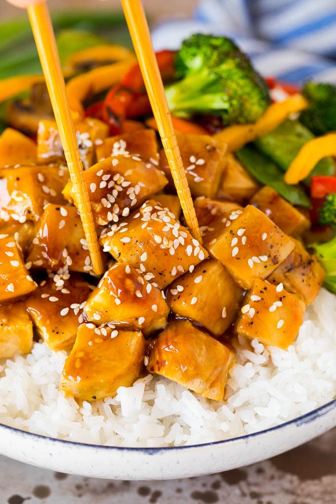This teriyaki chicken bowl recipe is diced chicken, colorful vegetables and steamed rice served with a homemade teriyaki sauce. A set of chopsticks in a teriyaki chicken bowl.