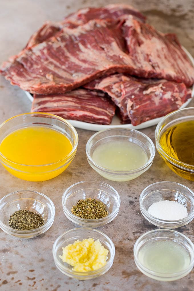 This churrasco recipe is marinated skirt steak that is grilled to tender perfection, then topped with a fresh and flavorful chimichurri sauce. Bowls of ingredients for marinade, and a plate of skirt steak.