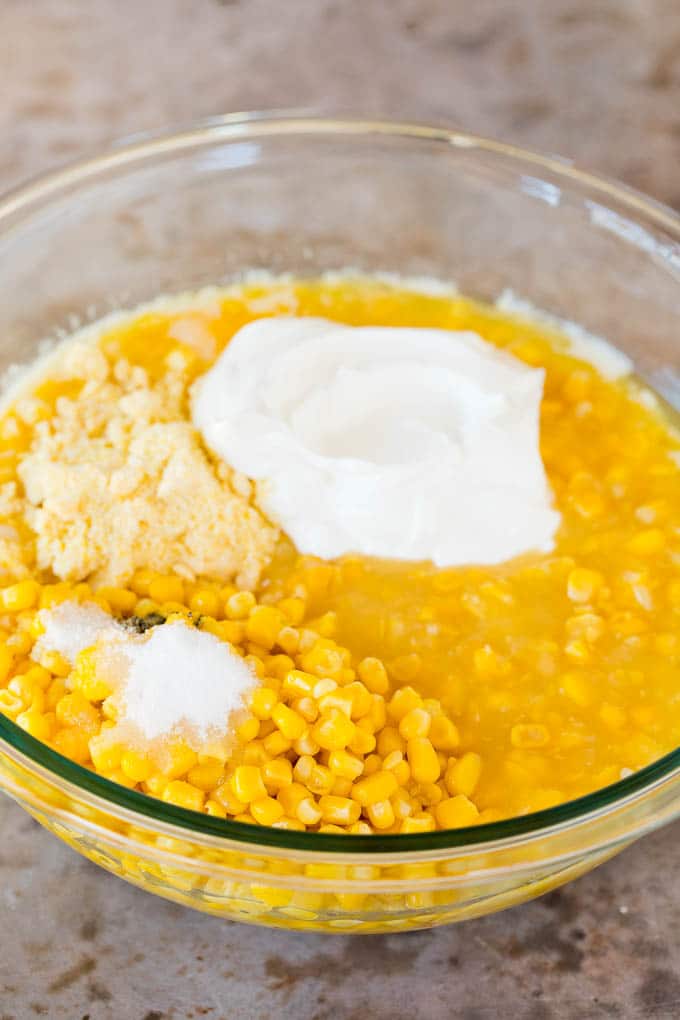 This cornbread casserole is a blend of corn muffin mix, canned corn, creamed corn, seasoning, eggs and butter, all baked together to make a hearty side dish. Corn, sour cream, corn muffin mix and sugar in a bowl.