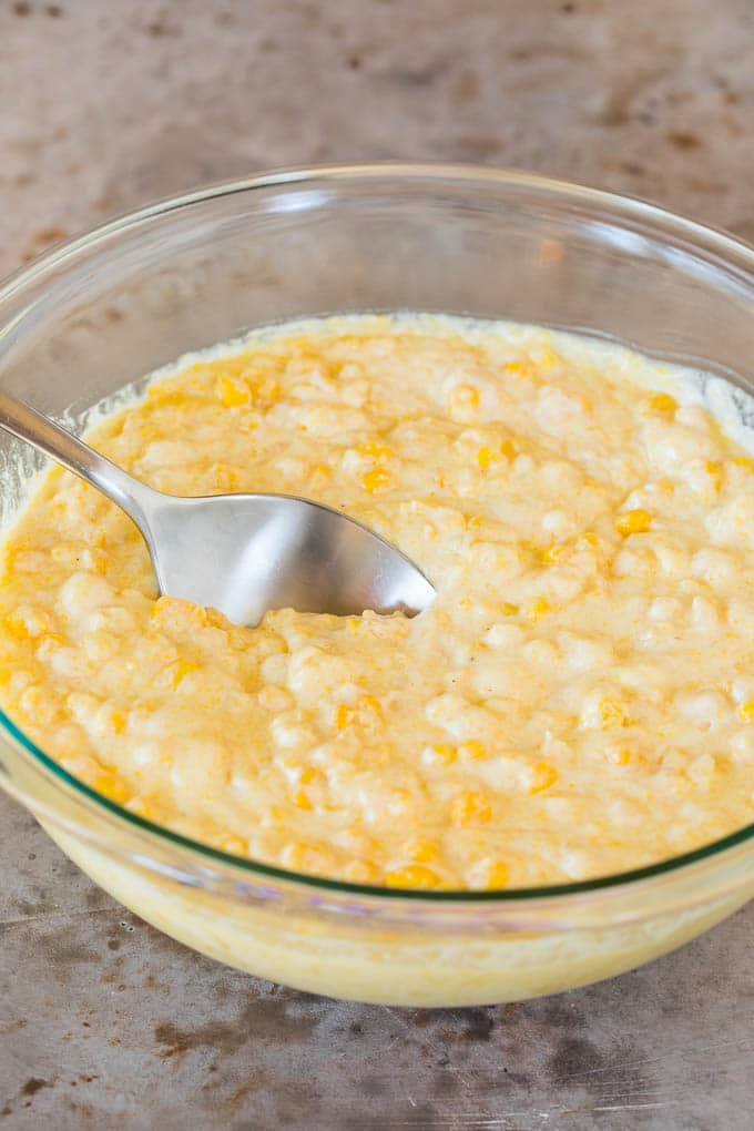 This cornbread casserole is a blend of corn muffin mix, canned corn, creamed corn, seasoning, eggs and butter, all baked together to make a hearty side dish. Cornbread batter in a mixing bowl.