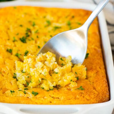 Cornbread casserole with a serving spoon in it.