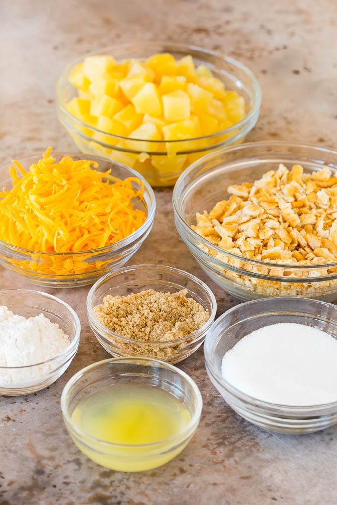This Southern pineapple casserole is pineapple, cheese and buttery crackers, all baked together to create a sweet and savory side dish. Bowls of pineapple, sugar, crackers and cheese.