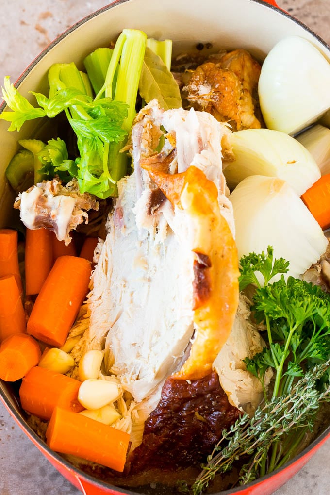 This turkey noodle soup is chunks of turkey, vegetables and pasta, all simmered together in a homemade broth. A turkey carcass in a pot with vegetables.