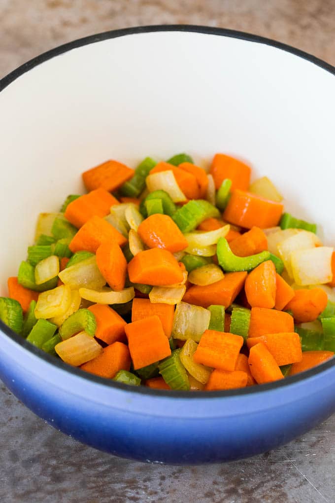 This turkey noodle soup is chunks of turkey, vegetables and pasta, all simmered together in a homemade broth. Sauteed carrots, onions and celery in a pot.