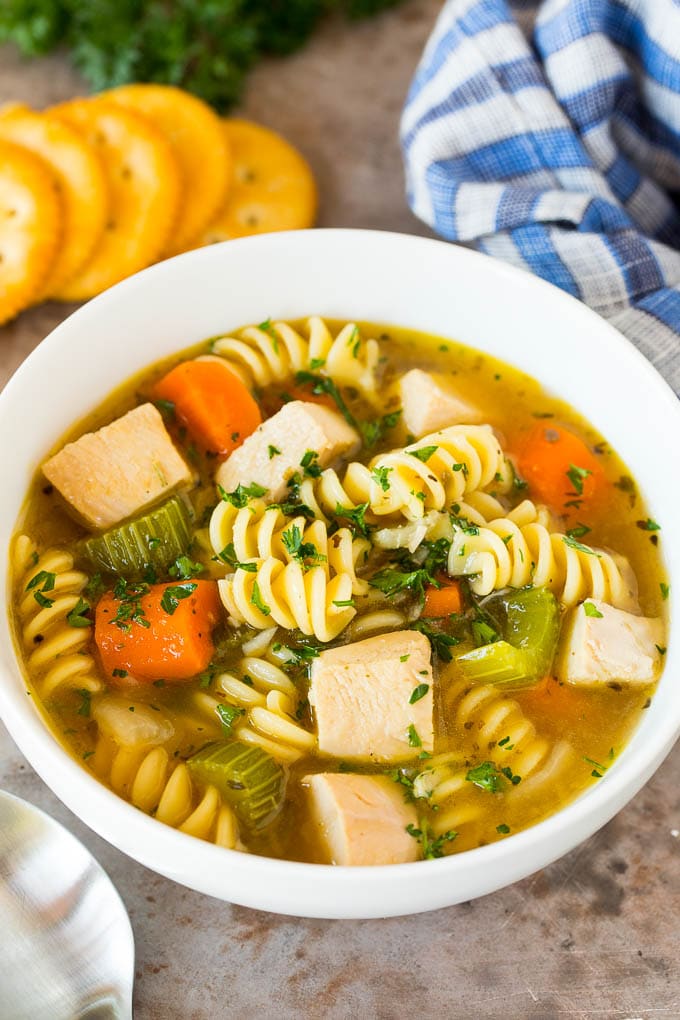 This turkey noodle soup is chunks of turkey, vegetables and pasta, all simmered together in a homemade broth. A bowl of turkey noodle soup served with parsley and crackers.