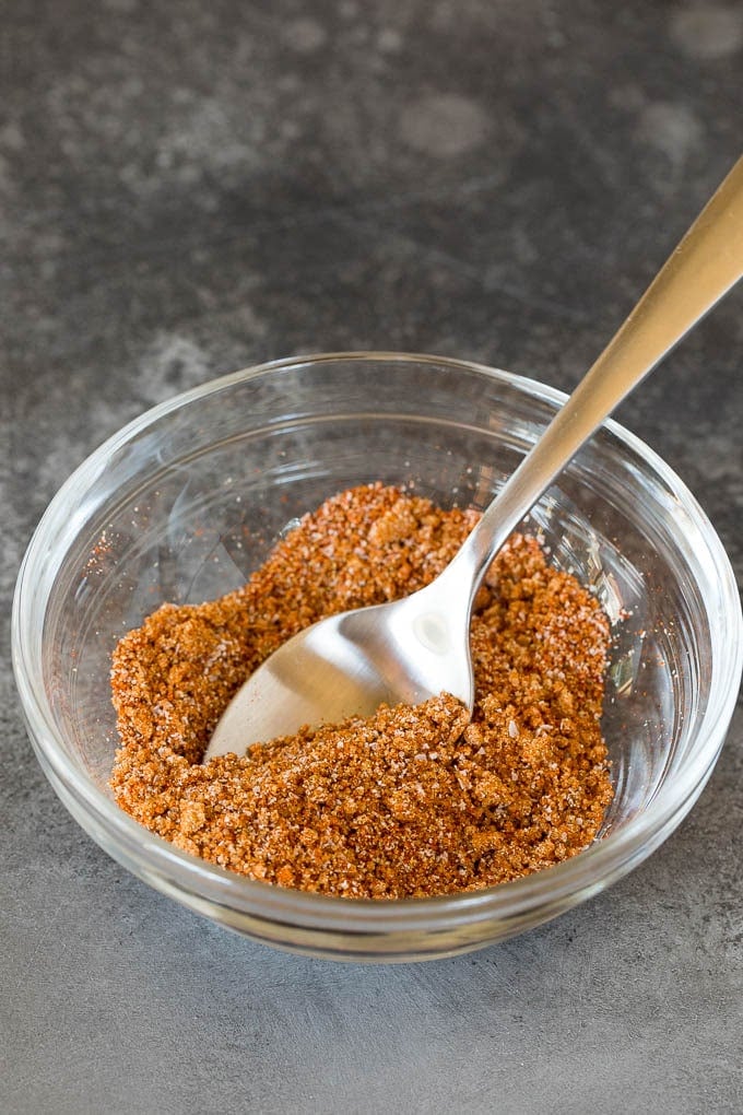 This air fryer salmon is fresh fish fillets topped with a homemade spice rub, then cooked to golden brown perfection. A spice blend in a bowl with a spoon.