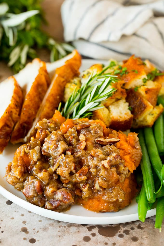 This crock pot sweet potato casserole is yams mashed with sweetener, vanilla and spices, then finished off with a brown sugar pecan topping. A plate of crock pot sweet potato casserole served with turkey and stuffing.
