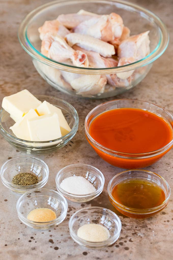 These air fryer chicken wings come out perfectly crispy every time, and cook so much faster than they would in a traditional oven. Bowls of chicken wings, hot sauce, butter and seasonings.