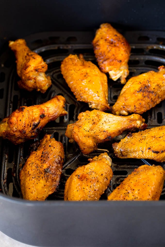 These air fryer chicken wings come out perfectly crispy every time, and cook so much faster than they would in a traditional oven. Cooked wings in the basket of an air fryer.