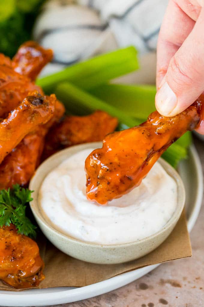 These air fryer chicken wings come out perfectly crispy every time, and cook so much faster than they would in a traditional oven. A hand dipping air fryer chicken wings into ranch sauce.
