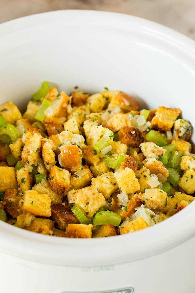 This crock pot stuffing is a mix of bread cubes, sauteed vegetables and seasonings, all placed in the slow cooker to create a flavorful and delicious side dish. Uncooked stuffing inside a crock pot.