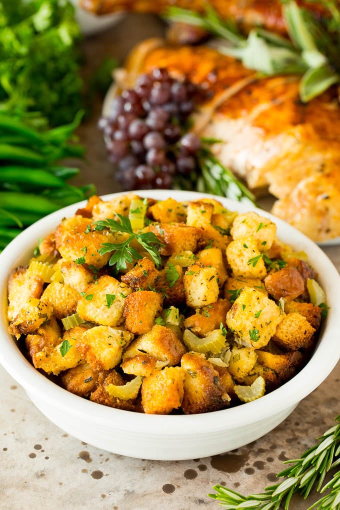 This crock pot stuffing is a mix of bread cubes, sauteed vegetables and seasonings, all placed in the slow cooker to create a flavorful and delicious side dish. A bowl of crock pot stuffing topped with fresh herbs.