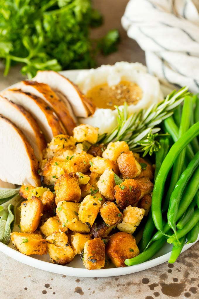 This crock pot stuffing is a mix of bread cubes, sauteed vegetables and seasonings, all placed in the slow cooker to create a flavorful and delicious side dish. Crock pot stuffing on a plate with turkey, green beans and mashed potatoes.