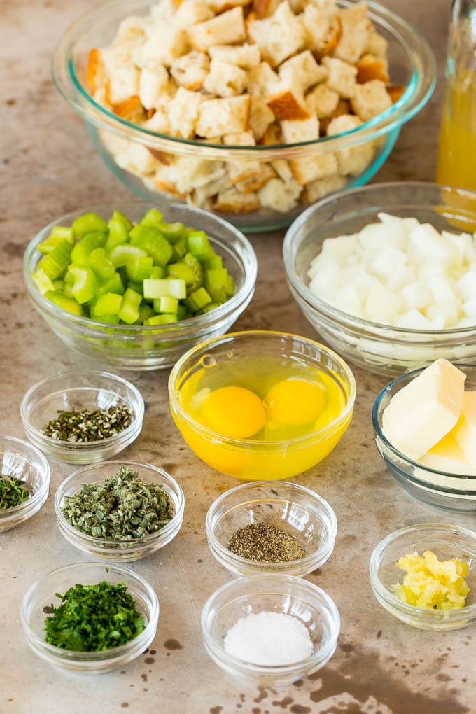 This Thanksgiving stuffing is a mixture of bread cubes, vegetables and plenty of herbs, all baked together until golden brown. Bowls of ingredients including bread cubes, vegetables and herbs.