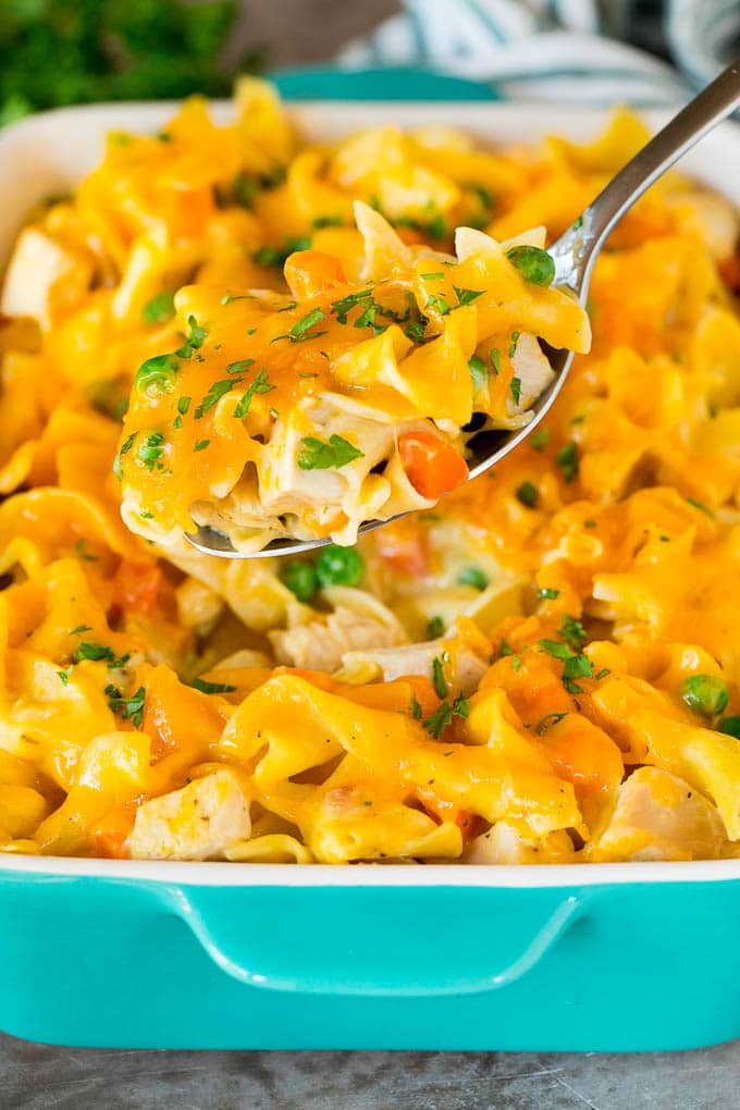 This turkey casserole is made with diced leftover turkey, egg noodles and vegetables, all tossed in a creamy cheesy sauce. A spoon serving up a portion of cheesy turkey casserole.