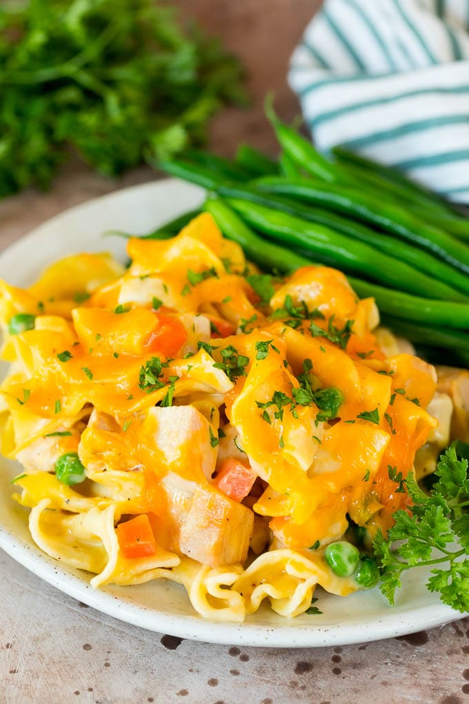 This turkey casserole is made with diced leftover turkey, egg noodles and vegetables, all tossed in a creamy cheesy sauce. Turkey casserole served on a plate with green beans.