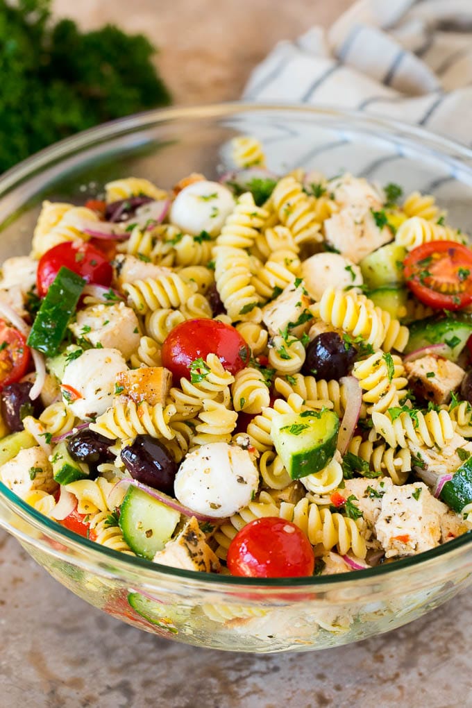 This chicken pasta salad is grilled chicken with olives, cheese and fresh vegetables, all tossed in a homemade Italian dressing. A bowl of chicken pasta salad with tomatoes, cucumbers and cheese.