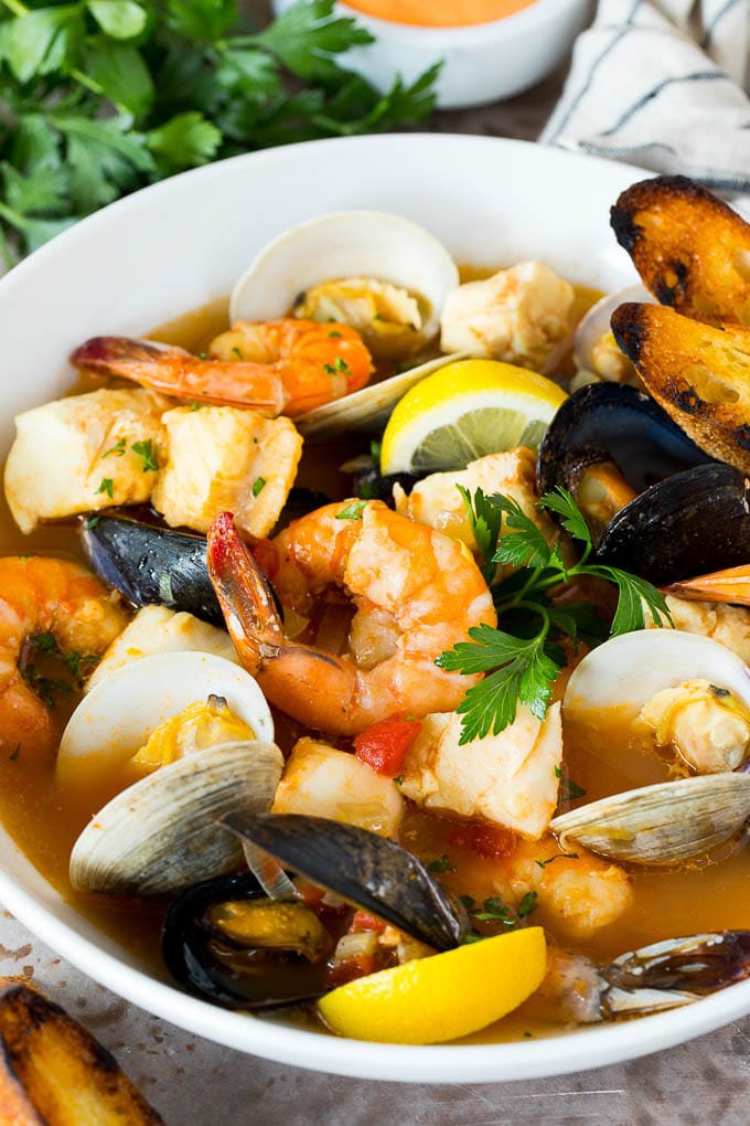 This bouillabaisse is French seafood stew with fresh fish, shrimp, clams and mussels, all simmered together in a flavorful broth. A serving bowl of bouillabaisse with shrimp, clams and fish.