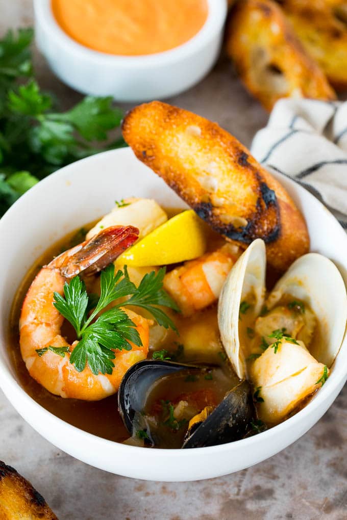 This bouillabaisse is French seafood stew with fresh fish, shrimp, clams and mussels, all simmered together in a flavorful broth. A bowl of bouillabaisse served with toasted bread slices.