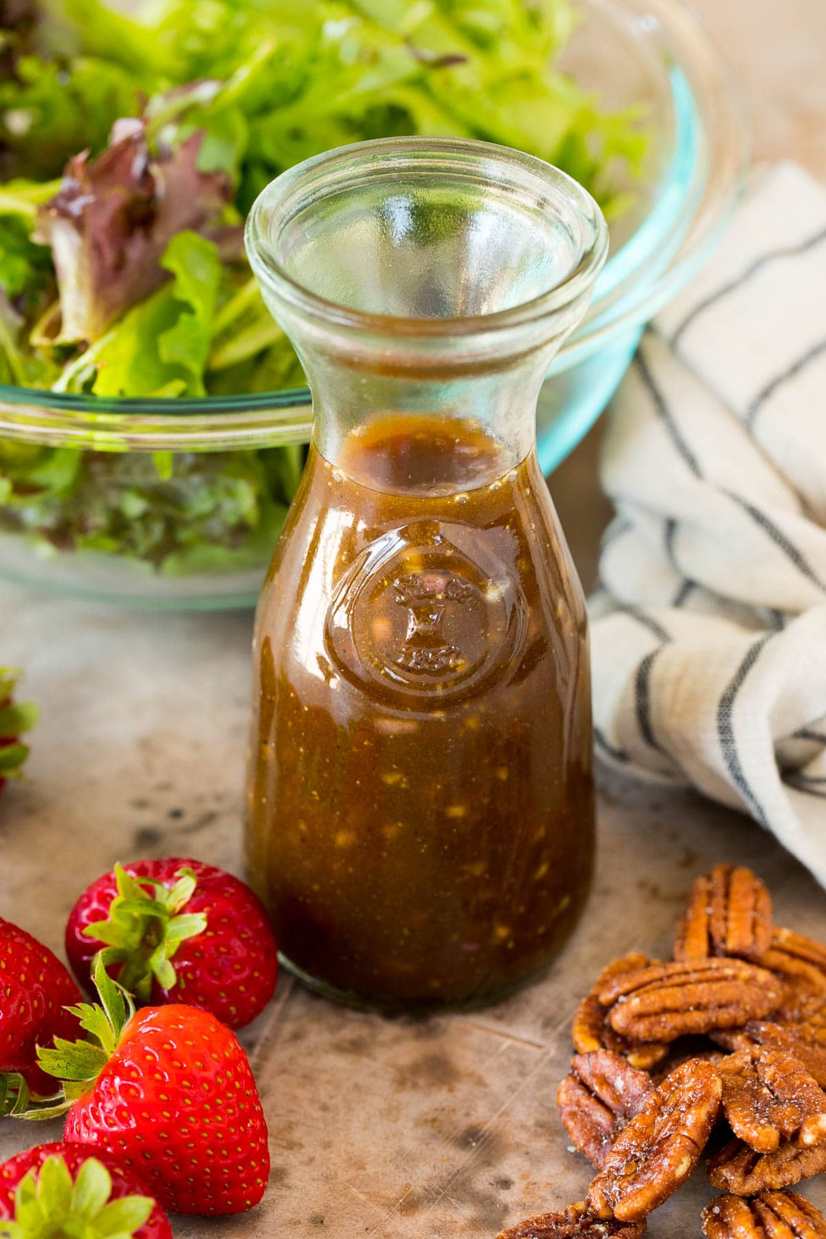 This balsamic vinaigrette is a flavorful dressing that adds bold flavor to salads, vegetables and even proteins. A bottle of balsamic vinaigrette surrounded by salad ingredients.