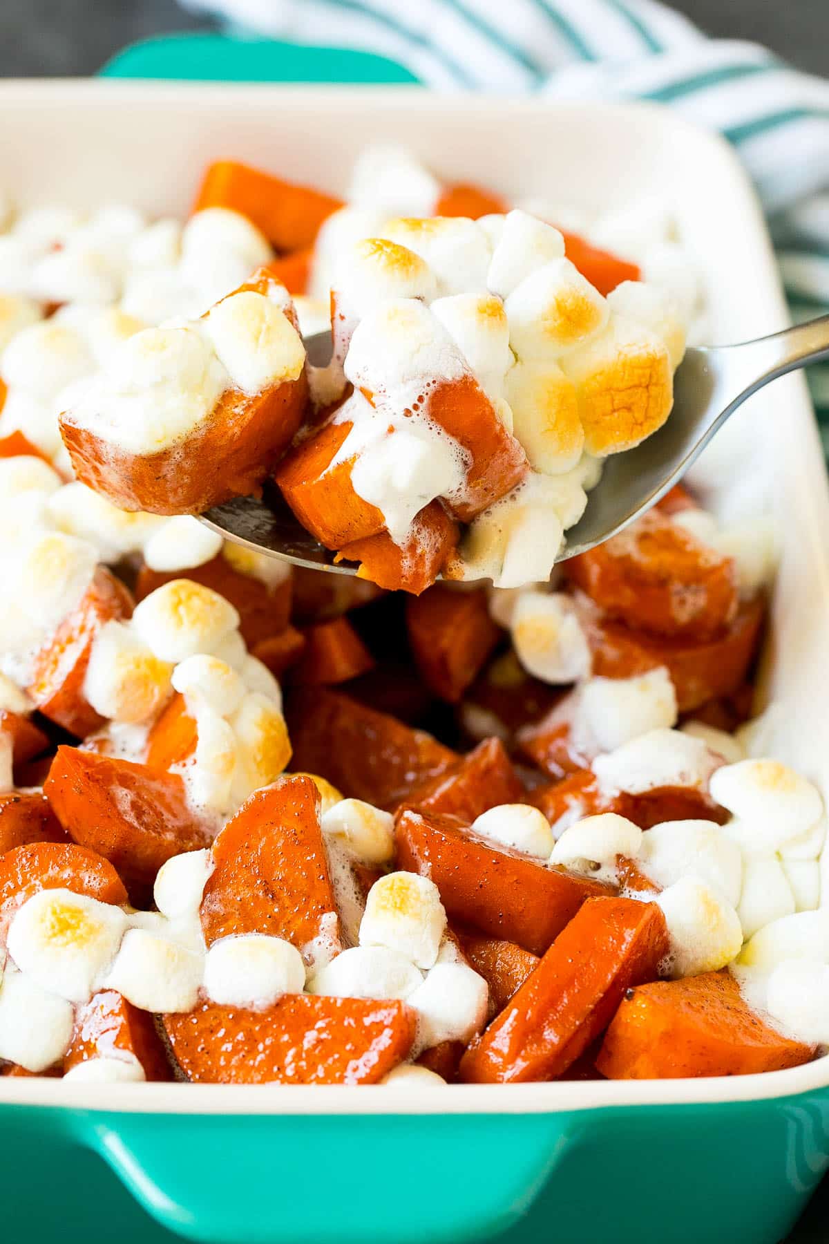 A spoon serving up a portion of candied yams.