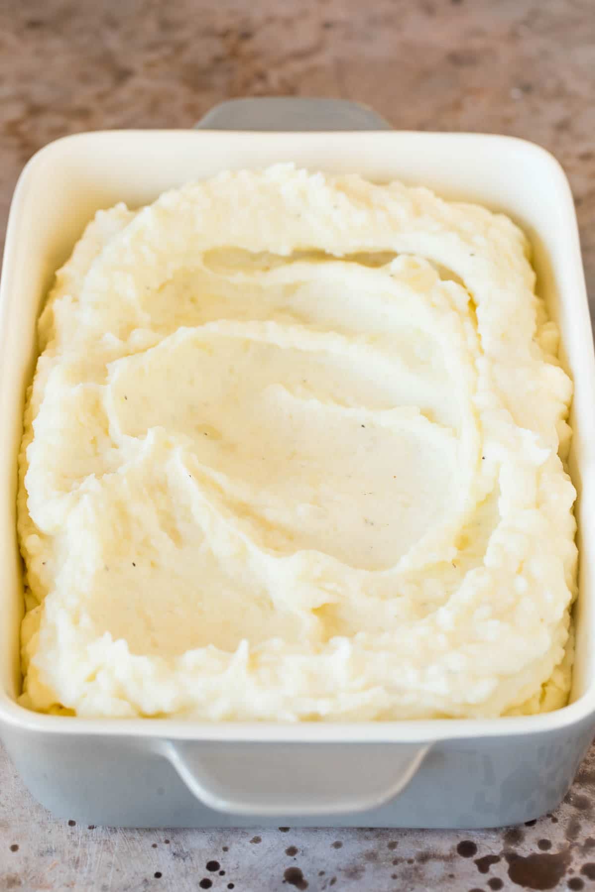 These make ahead mashed potatoes are Russet potatoes that are boiled until tender, then combined with butter, garlic, cream cheese and seasonings to make the ultimate side dish. Mashed up potatoes in a baking dish.