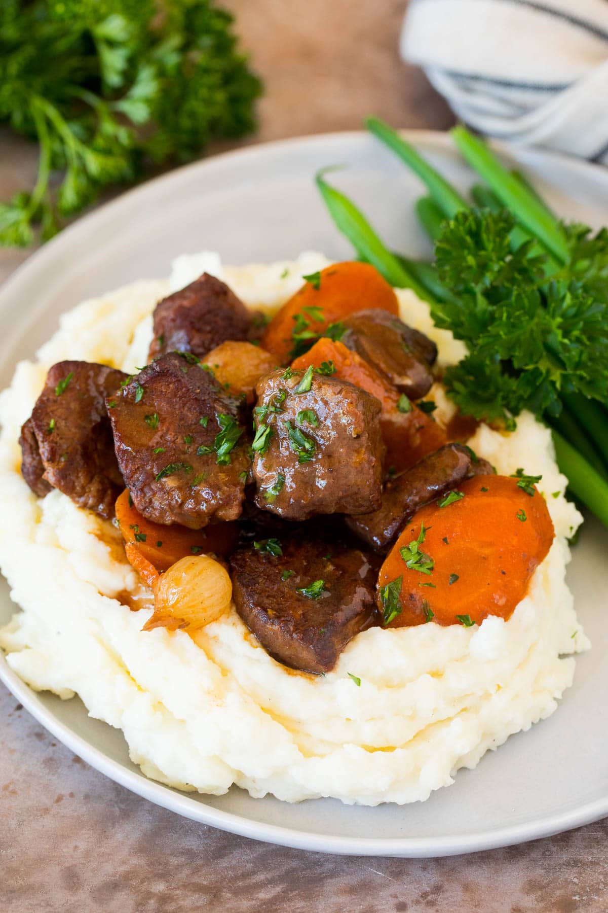 These make ahead mashed potatoes are Russet potatoes that are boiled until tender, then combined with butter, garlic, cream cheese and seasonings to make the ultimate side dish. Beef served over a pile of make ahead mashed potatoes.