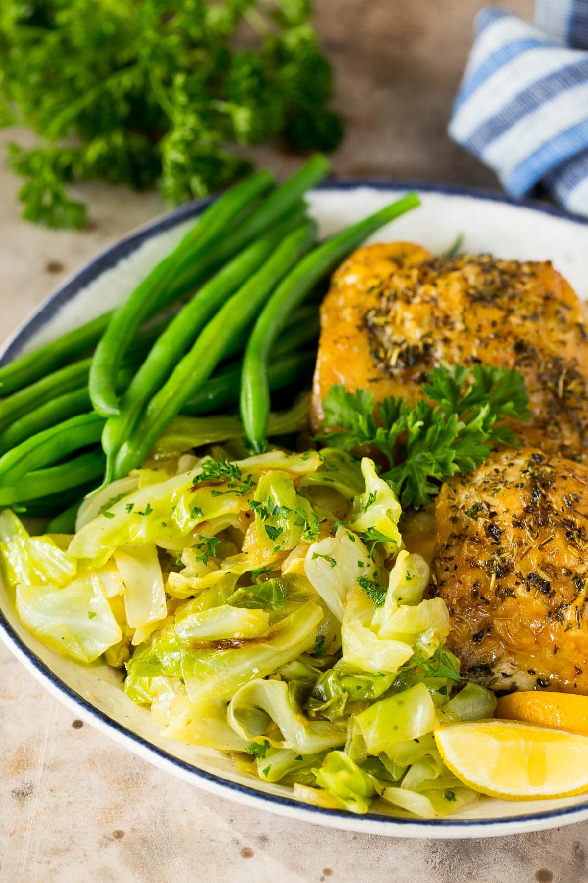 A plate of steamed green beans, chicken thighs and sauteed cabbage.