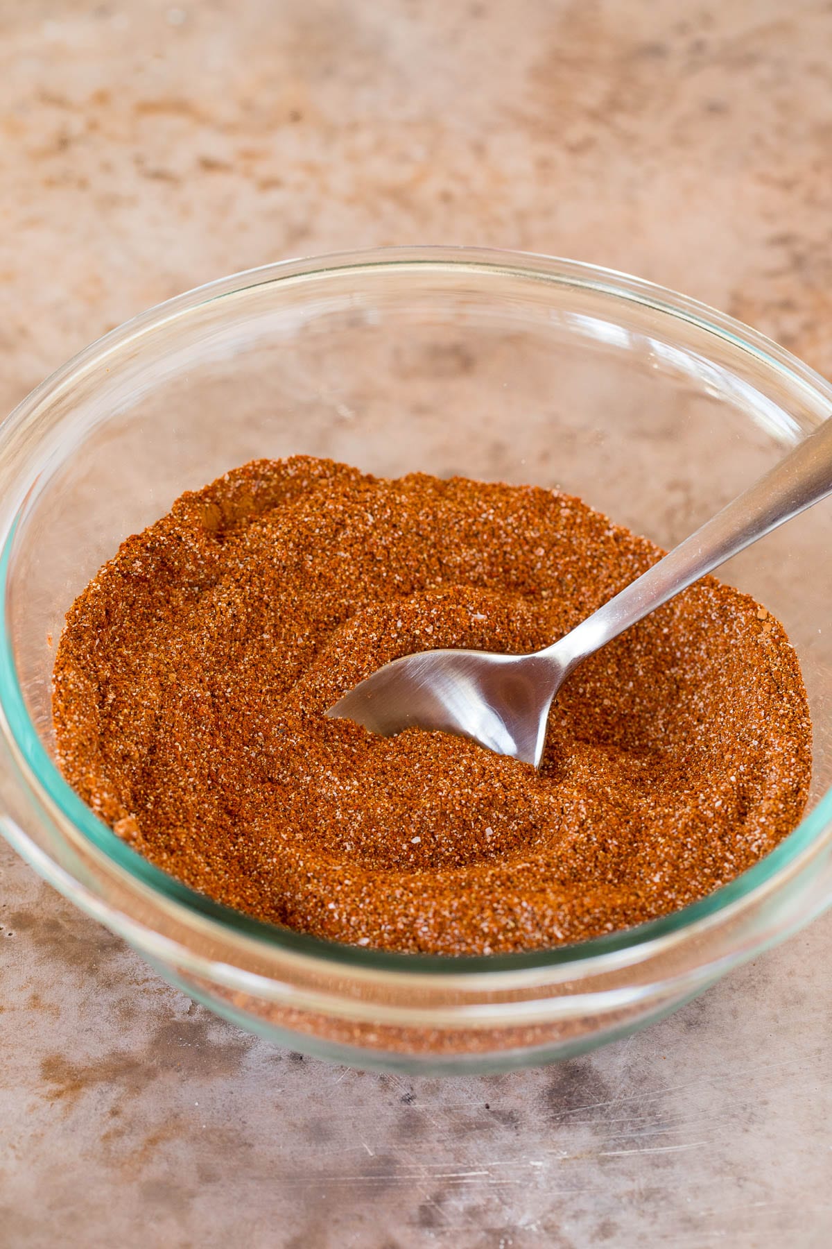 A bowl of seasoning with a spoon in it.