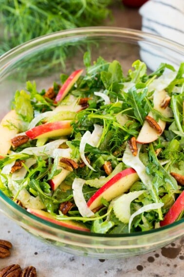A bowl of fennel salad made with arugula, apples and pecans.