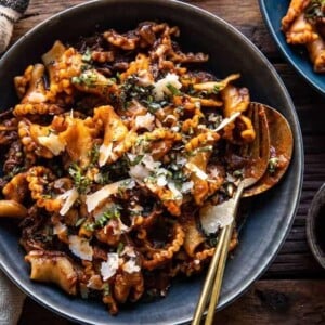 A picture of slow cooker red wine braised short rib pasta in a blue bowl with a fork and spoon.