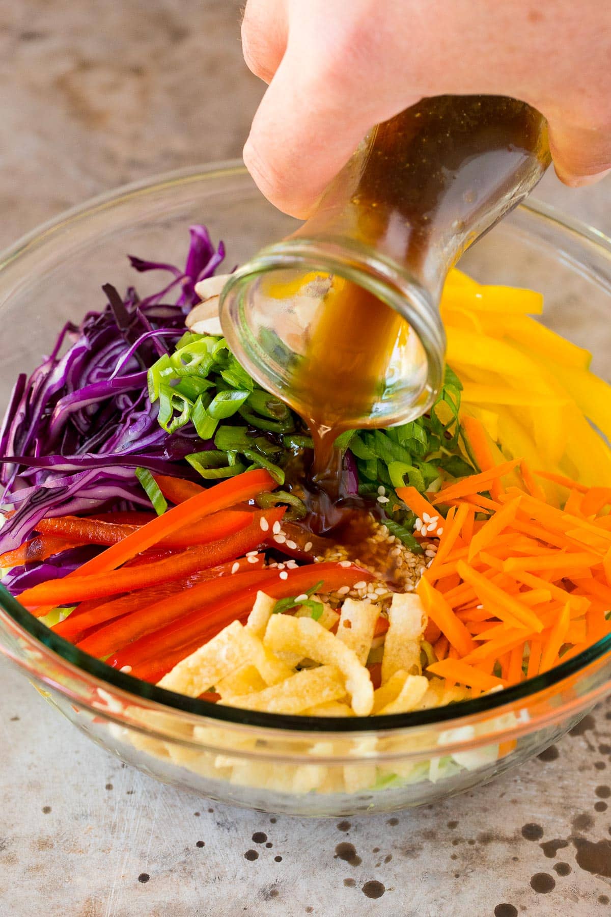 Dressing being poured over a vegetable salad.