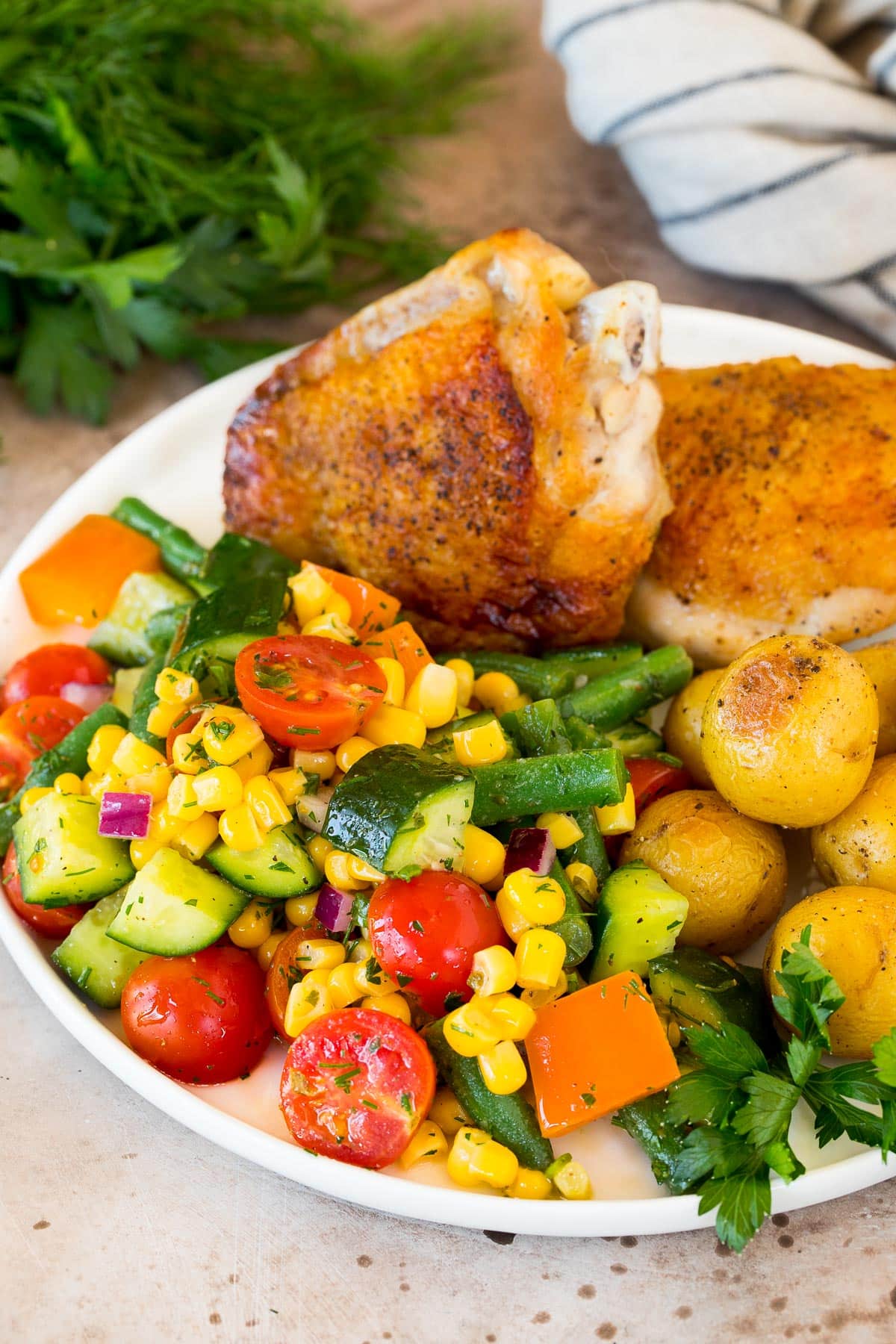 Veggie salad on a plate with chicken and potatoes.