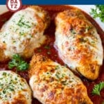 A pan of baked chicken parmesan which is golden brown crispy chicken breasts smothered in marinara sauce and melted cheese.