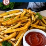A plate of baked french fries which are potato strips coated in oil and seasonings, then oven baked until golden brown and crispy.