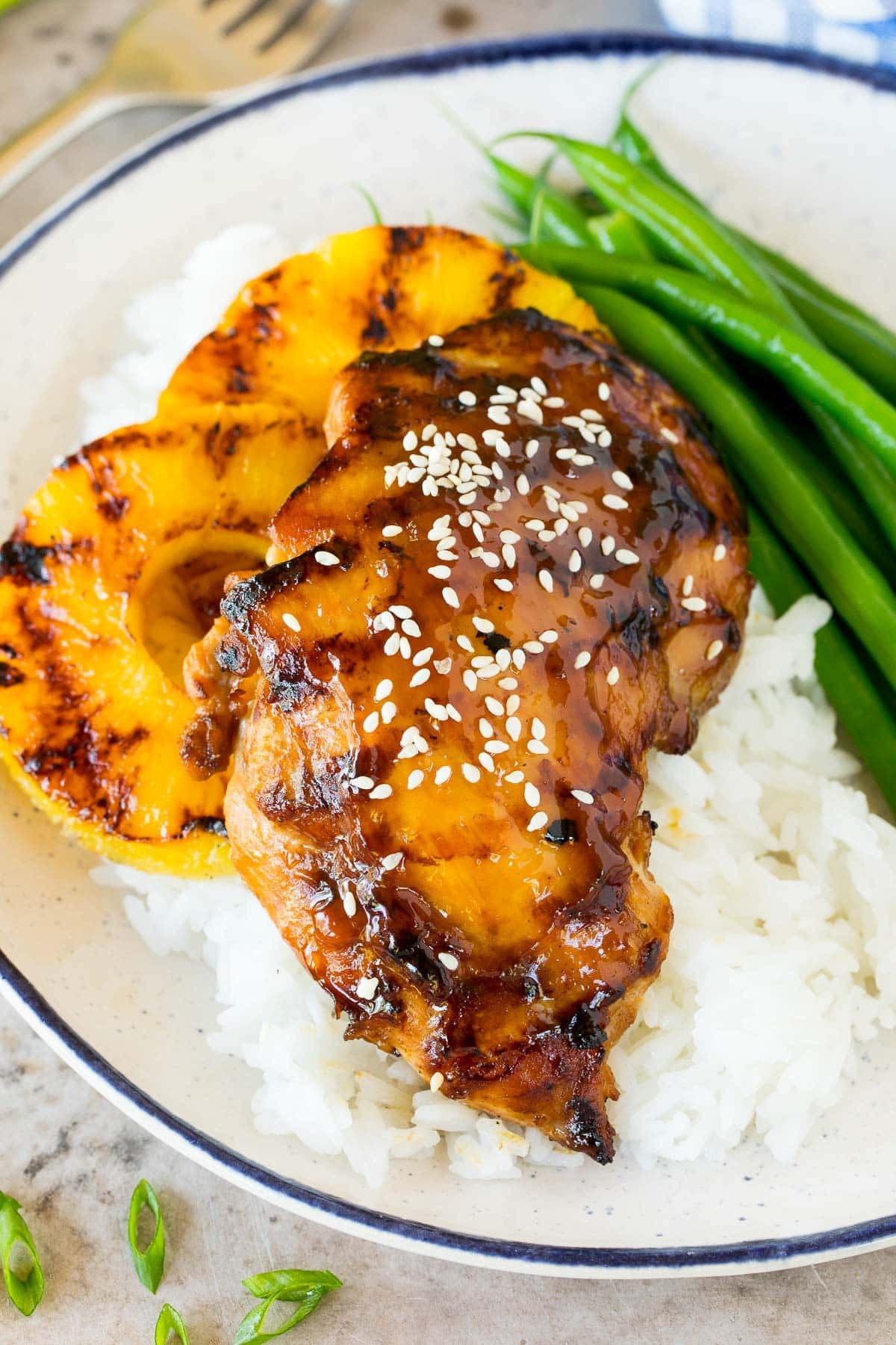 Chicken flavored with teriyaki marinade on a plate with rice and green beans.