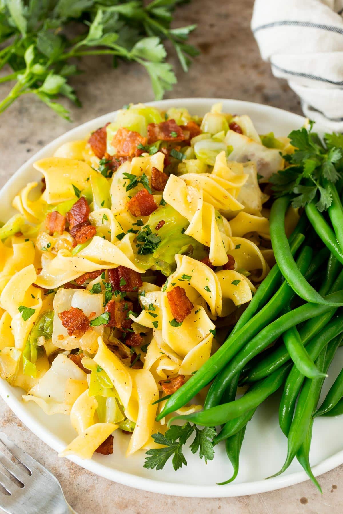 Haluski on a plate served with green beans.