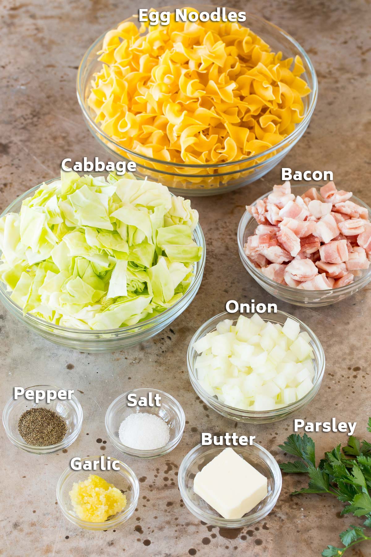 Bowls of ingredients including noodles, cabbage, bacon, onion and seasonings.