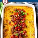 A baking dish filled with corn casserole and topped with bacon and diced bell peppers.