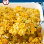 A spoon with a heaping serving of squash casserole over a baking dish with more casserole.