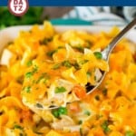 A baking dish full of turkey casserole with some of the casserole on a serving spoon.