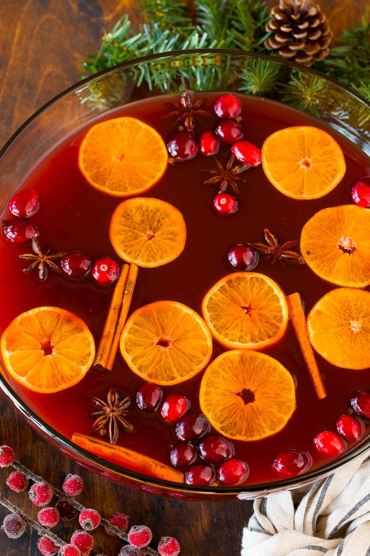 A bowl of Kinderpunsch garnished with orange slices, cinnamon sticks and cranberries.