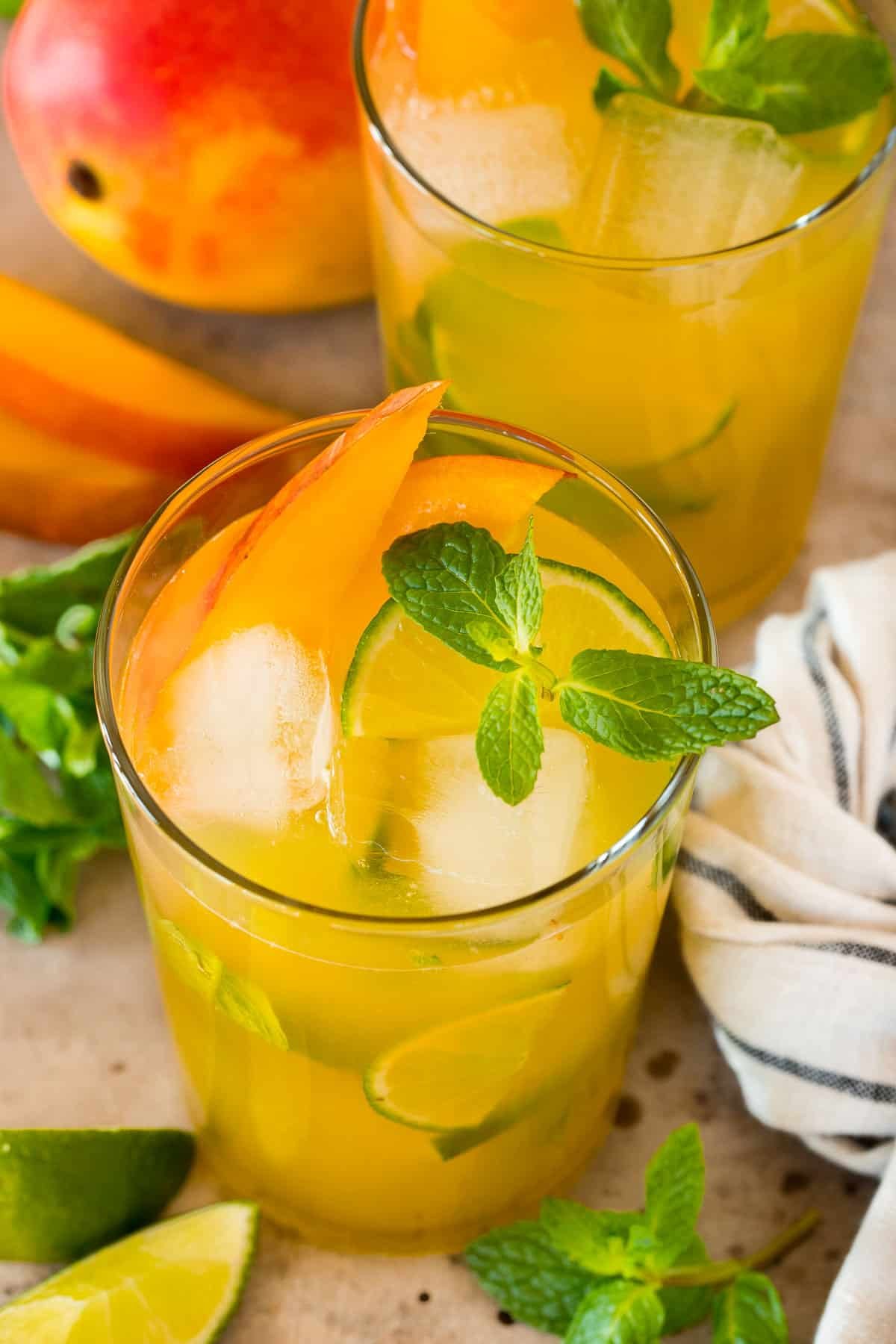 Cups of mango mojito with ice, mint and mango slices.